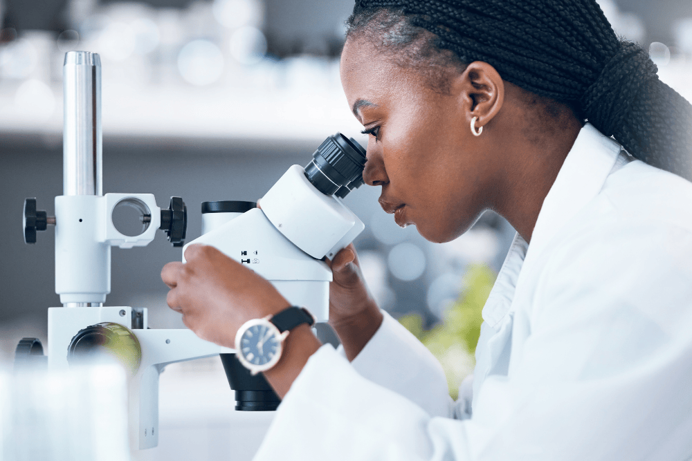 Female lab technician looking into microscope