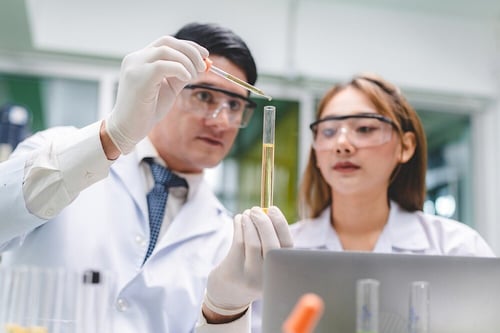 Two doctors in lab coats examining a sample together in a clinical setting.