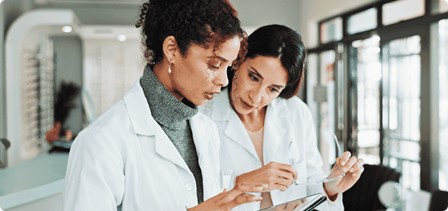 Two woman in labcoats looking at data