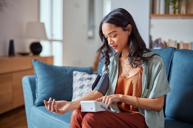 Woman takes blood pressure reading at home